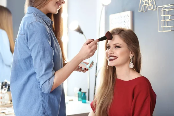 Profesionální make-up umělec, který pracuje s krásnou mladou ženou ve studiu — Stock fotografie