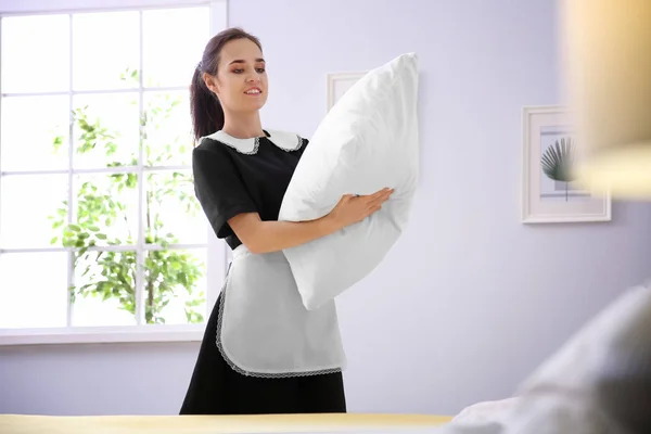 Jovem empregada fazendo cama no quarto do hotel — Fotografia de Stock