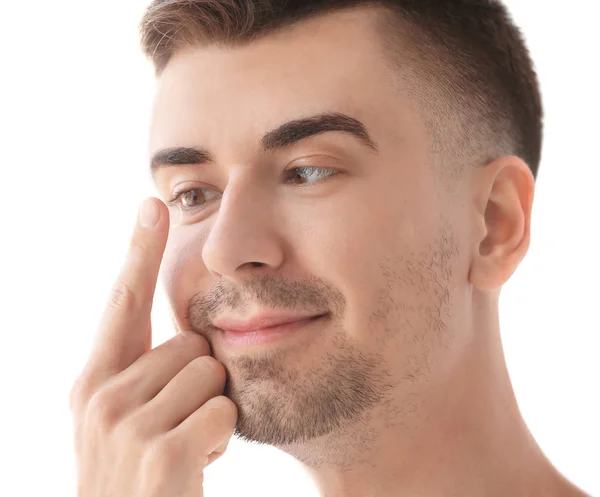 Junger Mann nimmt Kontaktlinse vor hellem Hintergrund ins Auge — Stockfoto