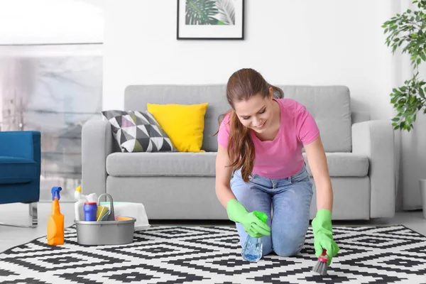 Woman cleaning carpet in living room — Stock Photo, Image