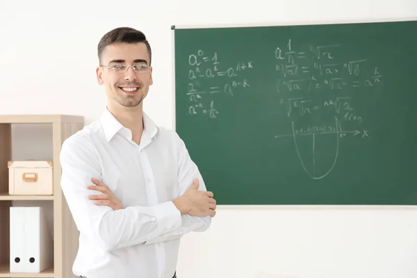 Joven profesor de pie cerca de pizarra en el aula —  Fotos de Stock