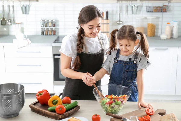 Молода няня з милою маленькою дівчинкою готує разом на кухні — стокове фото