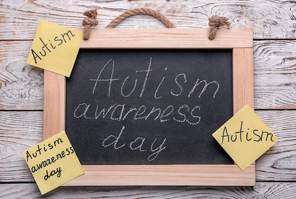 Schoolbord met zin "Autisme awareness day" op houten achtergrond — Stockfoto