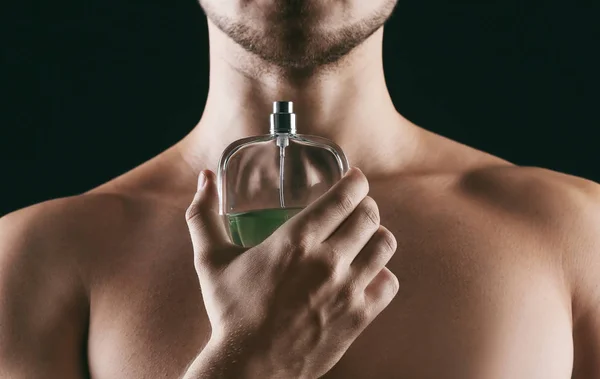 Bonito homem usando perfume no fundo preto, close-up — Fotografia de Stock