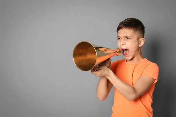 Schattige kleine jongen met megafoon op grijze achtergrond — Stockfoto