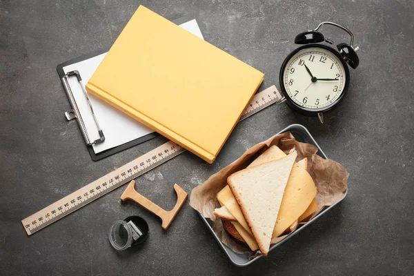 Composizione flat lay con lunch box, sandwich e cancelleria su fondo grigio — Foto Stock