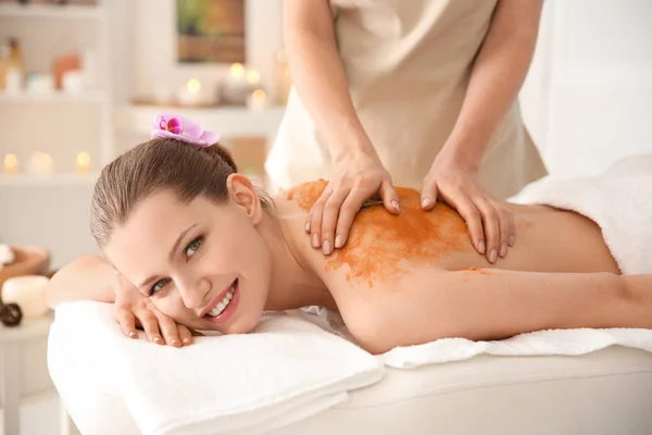 Belle jeune femme ayant massage avec gommage du corps dans le salon de spa — Photo