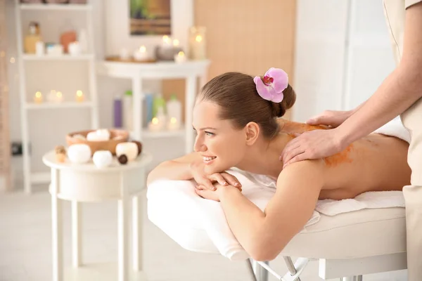 Beautiful young woman having massage with body scrub in spa salon — Stock Photo, Image