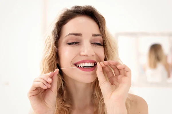 Wanita muda flossing giginya di dalam ruangan — Stok Foto