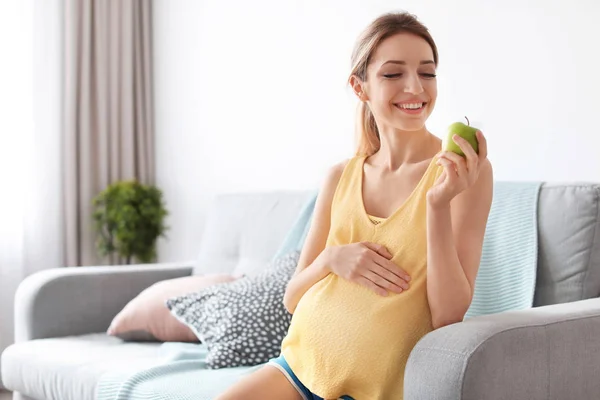 Giovane donna incinta che tiene la mela a casa — Foto Stock