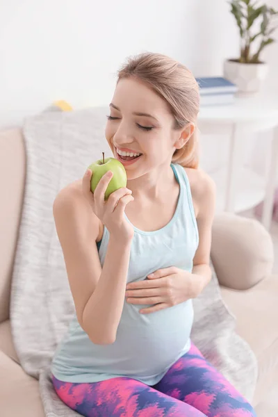 Young pregnant woman eating apple at home — Stock Photo, Image