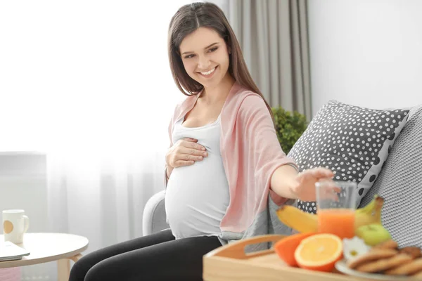 Jovem grávida tomando vidro com suco em casa — Fotografia de Stock
