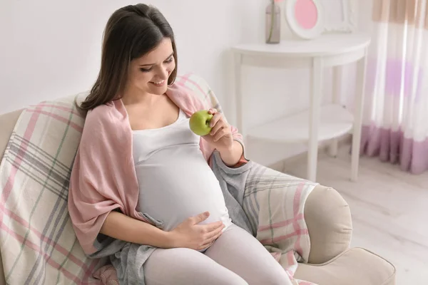 Jovem grávida segurando maçã em casa — Fotografia de Stock