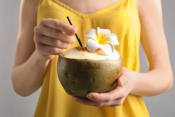 Jeune femme avec cocktail de noix de coco fraîche sur fond flou, gros plan — Photo