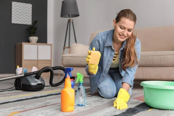 Young woman cleaning carpet at home — Stock Photo, Image