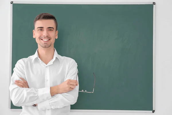 Mladý muž učitel stojící poblíž tabule na bílém pozadí — Stock fotografie