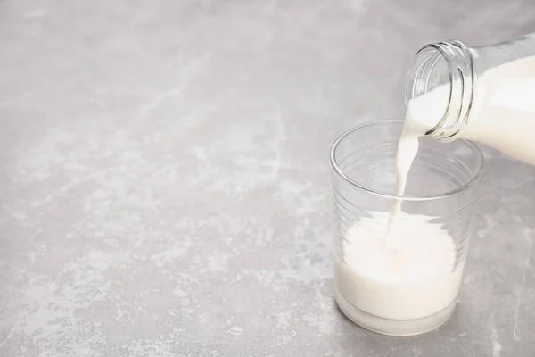Despejo de leite de garrafa em vidro na mesa. Produtos lácteos frescos — Fotografia de Stock