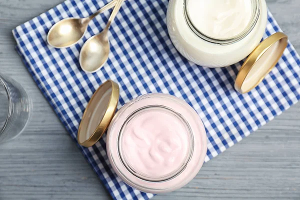 Frascos com iogurte saboroso na mesa, vista superior — Fotografia de Stock