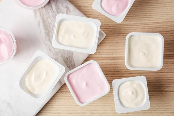 Plastik cangkir dengan yogurt lezat di atas meja, tampilan atas — Stok Foto