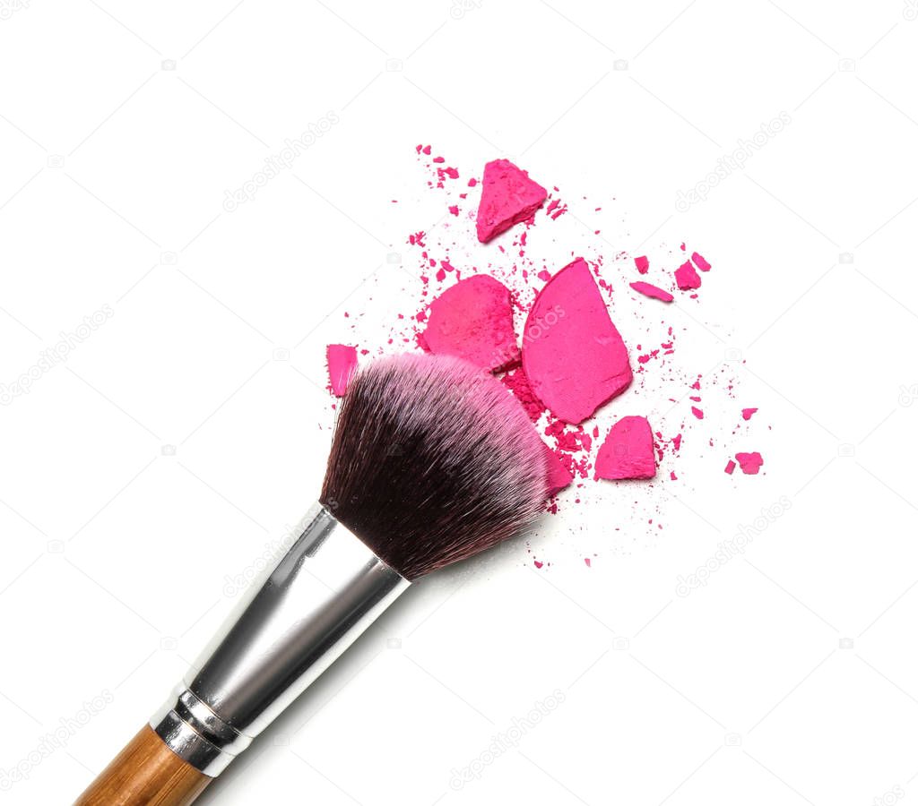 Makeup brush and crushed cosmetic product on white background, top view