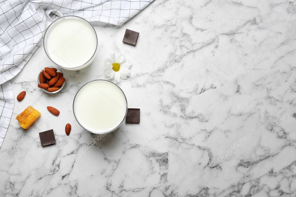 Glasses with milk, nuts and chocolate pieces on light background