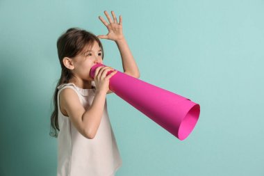 Renk arka plan üzerinde kağıt megafon ile sevimli küçük kız