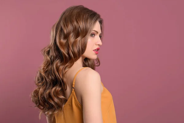 Portret van een jonge vrouw met lange mooie haren op kleur achtergrond — Stockfoto