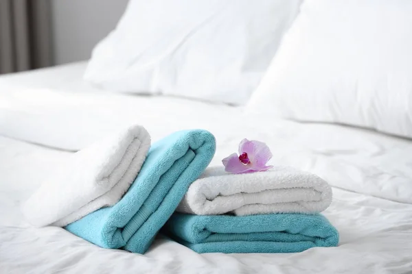 Toallas limpias y orquídea rosa en la cama — Foto de Stock
