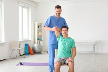 Klinikte erkek hastalarla çalışan fizyoterapist.