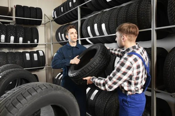 Jonge mannelijke mechanica met autobanden in auto servicecentrum — Stockfoto