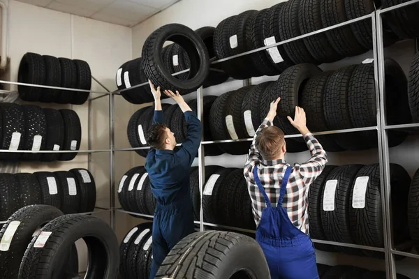 Jovens mecânicos masculinos com pneus de carro no centro de serviços de automóveis — Fotografia de Stock