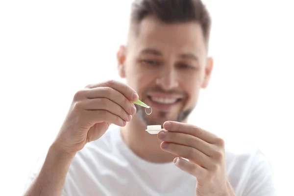 Jonge man bedrijf contactlens zaak op lichte achtergrond — Stockfoto