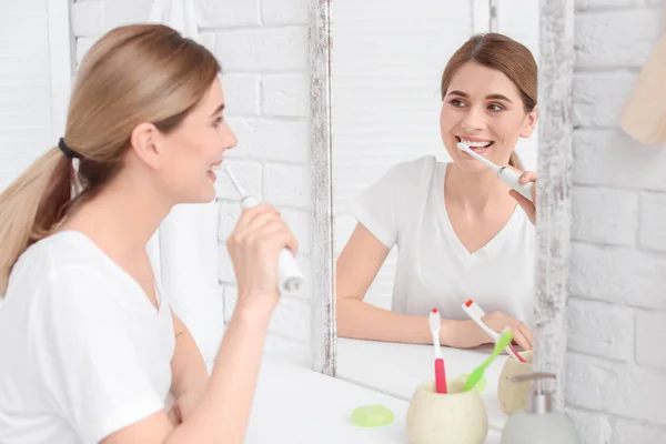 Wanita muda menggosok giginya di kamar mandi — Stok Foto