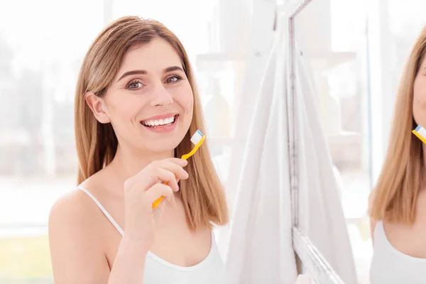 Young woman brushing her teeth in bathroom — Stock Photo, Image