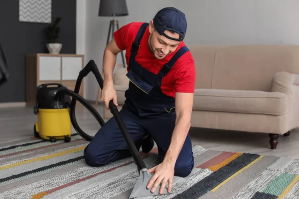 Mogen man hoovering mattan med dammsugare i vardagsrum — Stockfoto