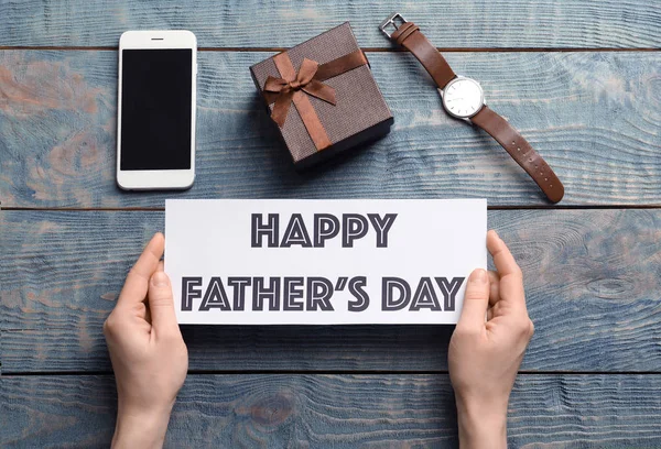 Man holding card with words HAPPY FATHER'S DAY over table with gifts, top view — Stock Photo, Image