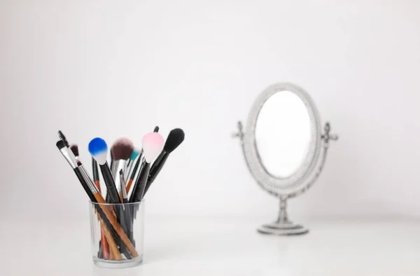 Houder met make up borstels op tafel — Stockfoto