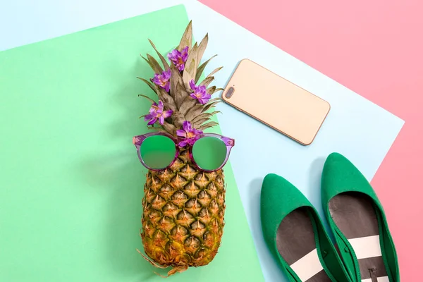 Composition à plat avec ananas mûr, lunettes de soleil, chaussures et téléphone portable sur fond de couleur — Photo