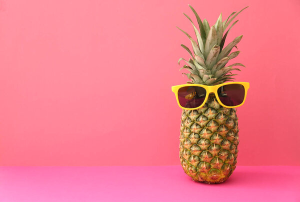 Fresh ripe pineapple with sunglasses on color background