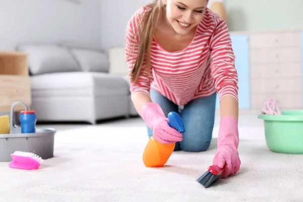 Mujer joven limpieza de alfombras en casa — Foto de Stock