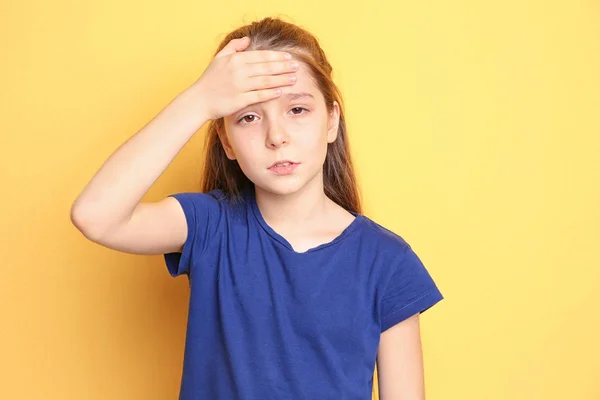 Маленька дівчинка страждає від головного болю на кольоровому фоні — стокове фото