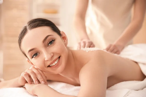 Hermosa mujer joven teniendo masaje con exfoliante corporal en el salón de spa — Foto de Stock