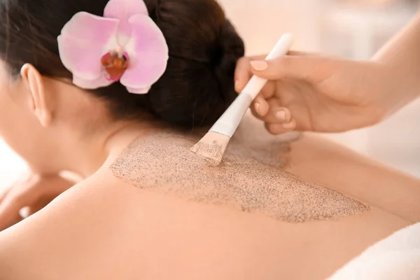 Hermosa mujer joven teniendo masaje con exfoliante corporal en el salón de spa — Foto de Stock