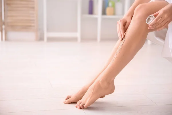 Γυναίκα εφαρμόζοντας scrub σώματος στα πόδια στο σπίτι — Φωτογραφία Αρχείου