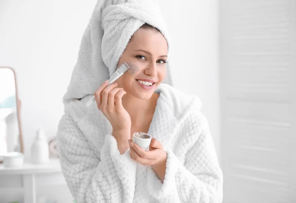 Mujer aplicando exfoliante en la cara en el baño —  Fotos de Stock