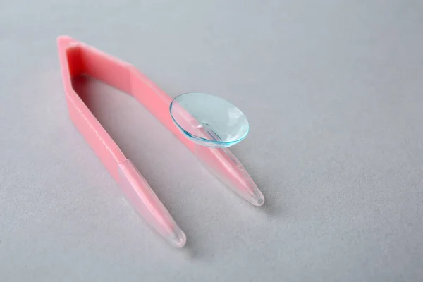 Tweezers with contact lens on light background — Stock Photo, Image