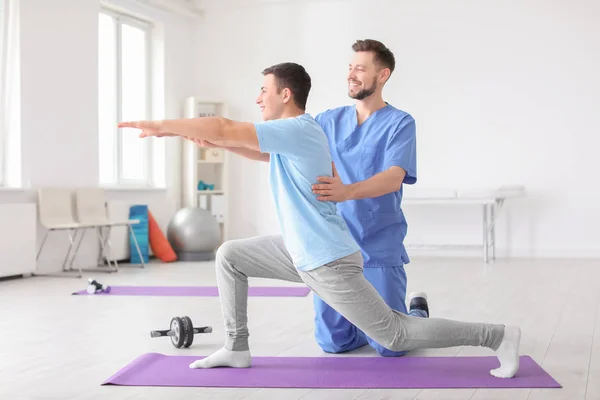 Fisioterapeuta trabajando con paciente masculino en clínica —  Fotos de Stock