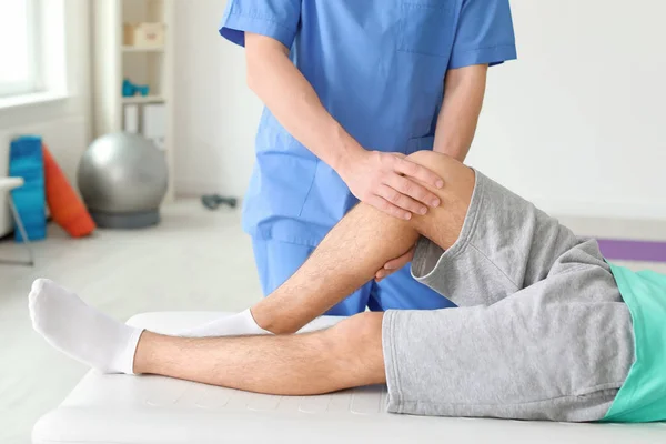 Fisioterapeuta trabajando con paciente masculino en clínica — Foto de Stock