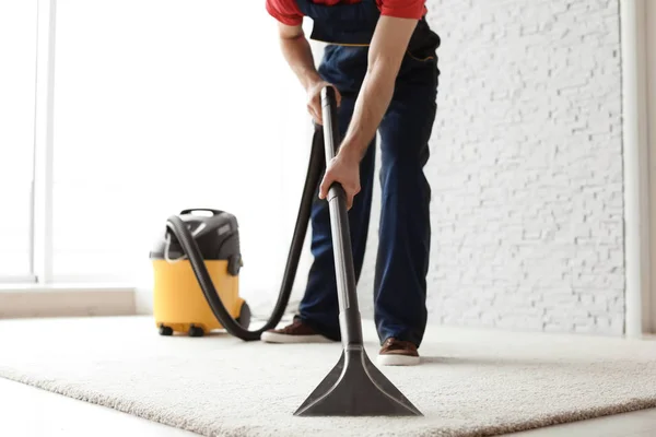 Masculino trabajador limpieza alfombra con vacío en interiores — Foto de Stock