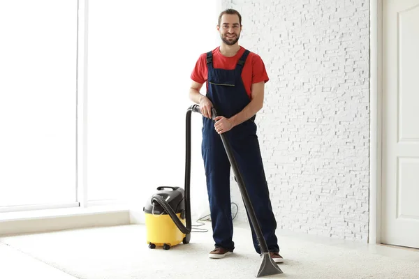 Trabalhador masculino tapete de limpeza com vácuo dentro de casa — Fotografia de Stock